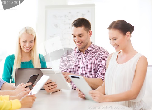 Image of smiling team with table pc and laptop in office