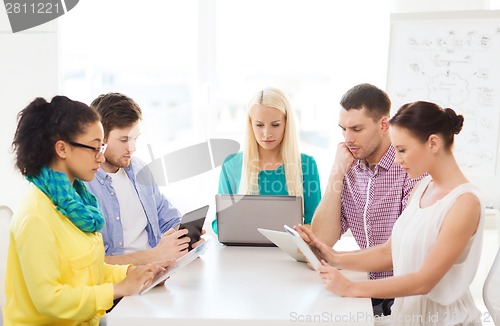 Image of serious team with table pc and laptop in office