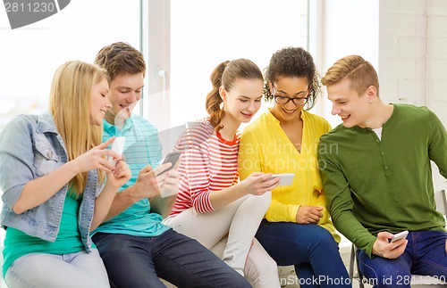 Image of smiling students with smartphone texting at school