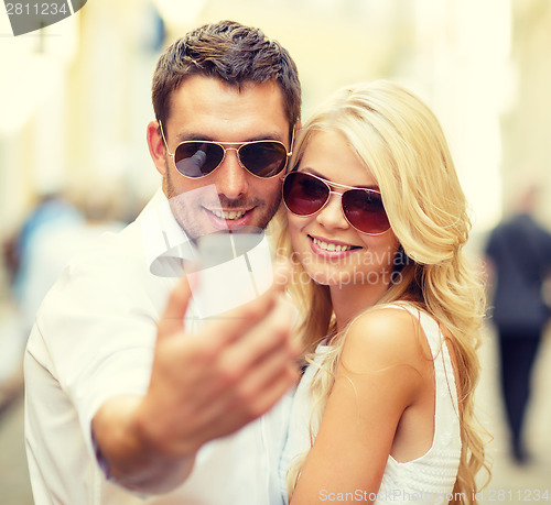 Image of smiling couple with smartphone in the city