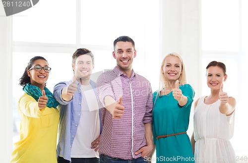Image of happy creative team showing thumbs up in office