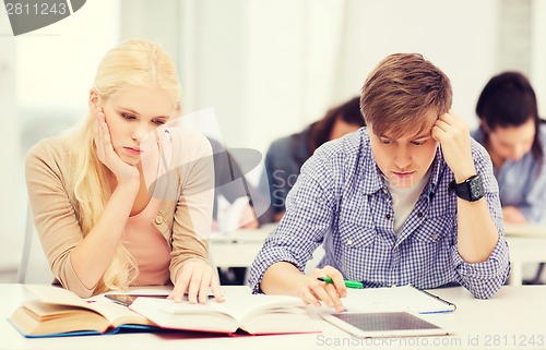 Image of tired students with tablet pc, notebooks and books