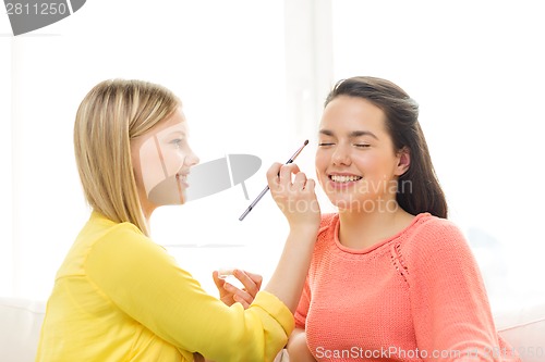 Image of two smiling teenage girls applying make up at home