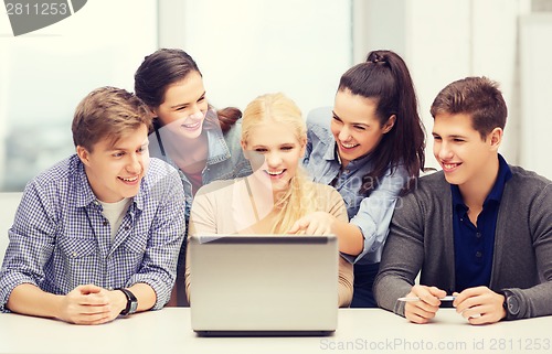 Image of smiling students looking at laptop at school