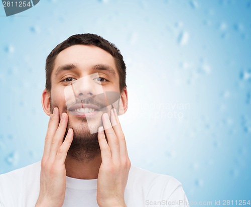 Image of beautiful smiling man touching his face