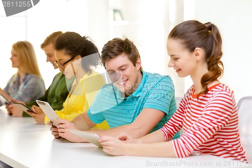 Image of smiling students looking at tablet pc at school