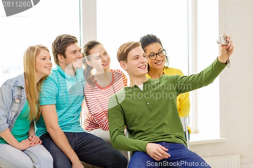 Image of five smiling students taking picture with camera