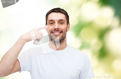 Image of smiling young handsome man pointing to eyes