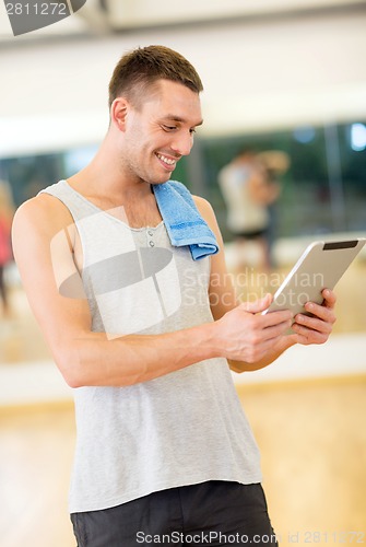 Image of young man with tablet pc computer and towel in gym