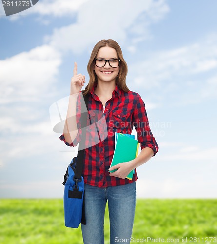 Image of smiling female student with bag and notebooks