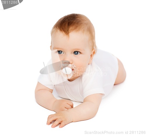 Image of smiling baby lying on floor with dummy in mouth