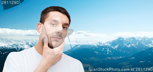 Image of beautiful calm man touching his face