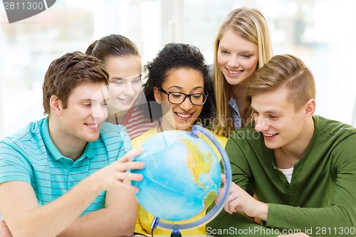 Image of five smiling student looking at globe at school