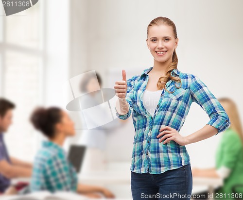 Image of young woman in casual clothes showing thumbs up