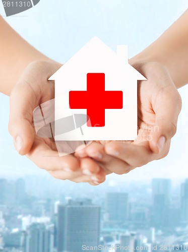 Image of hands holding paper house with red cross