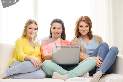 Image of three smiling teenage girls with laptop at home