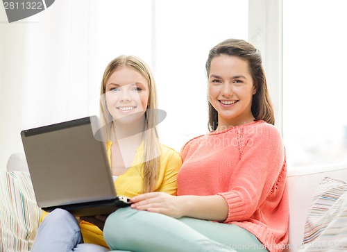 Image of two smiling teenage girls with laptop at home