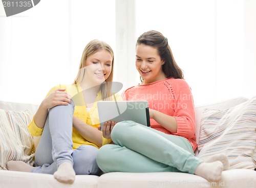 Image of two smiling teenage girls with tablet pc at home