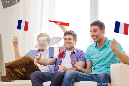 Image of happy male friends with flags and vuvuzela