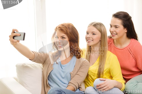 Image of smiling teenage girls with smartphone at home