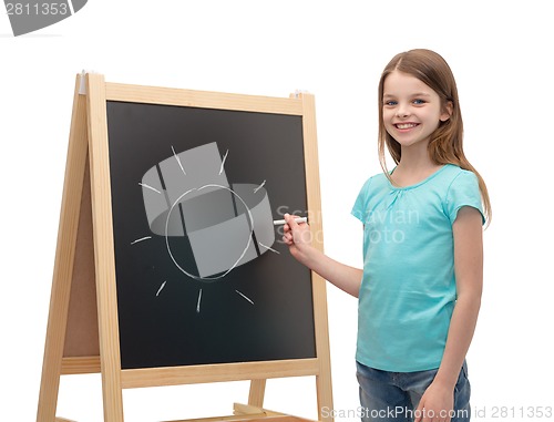 Image of happy little girl with sun drawn on blackboard