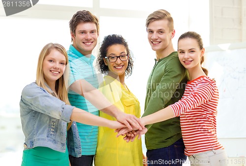 Image of smiling students with hands on top of each other