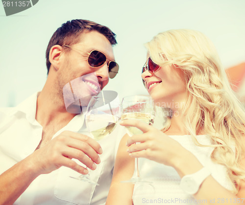 Image of smiling couple in sunglasses drinking wine in cafe