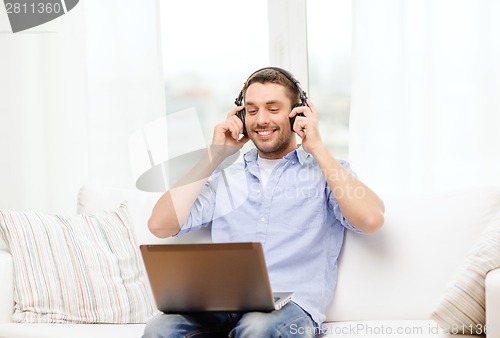 Image of smiling man with laptop and headphones at home