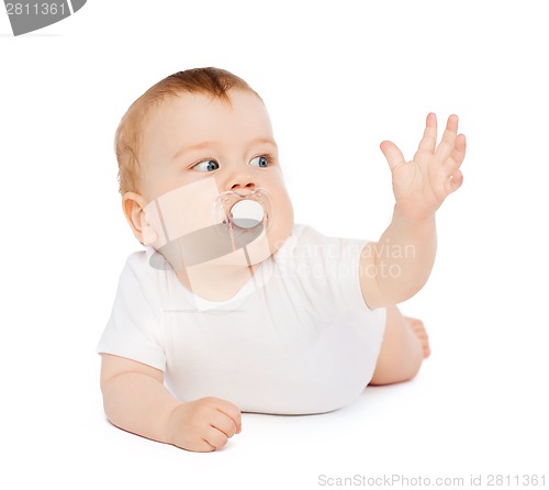 Image of smiling baby lying on floor with dummy in mouth