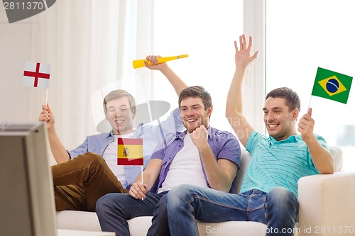 Image of happy male friends with flags and vuvuzela