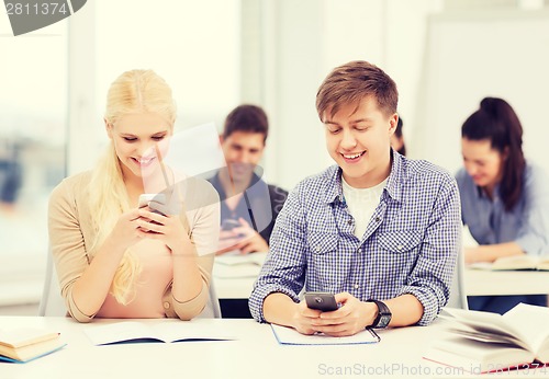 Image of students looking into smartphone at school