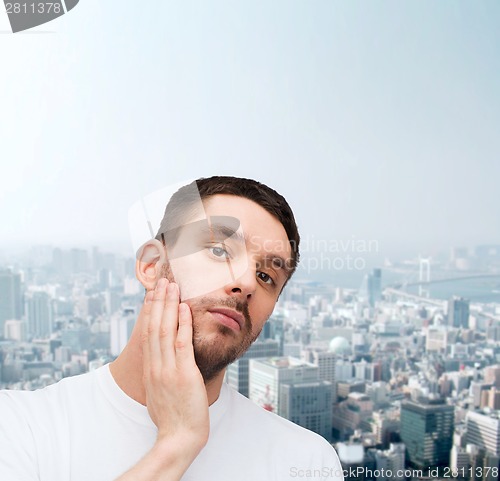 Image of beautiful calm man touching his face