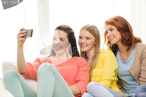 Image of smiling teenage girls with smartphone at home