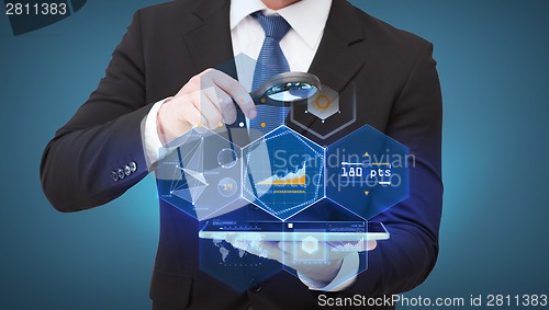 Image of businessman hand holding magnifier over tablet pc