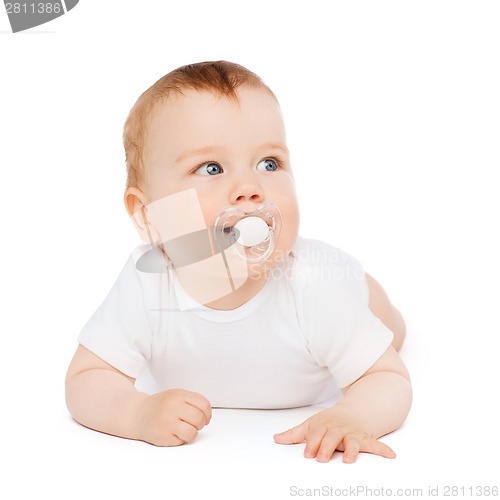 Image of smiling baby lying on floor with dummy in mouth