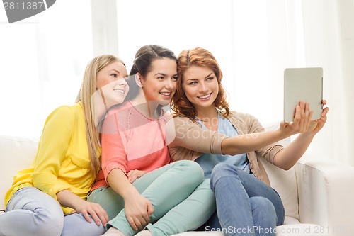 Image of three smiling teenage girls with tablet pc at home