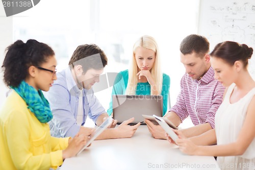 Image of serious team with table pc and laptop in office