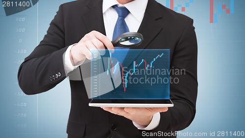 Image of businessman hand holding magnifier over tablet pc