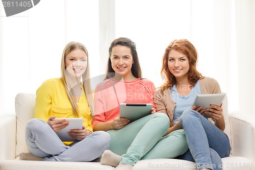 Image of three smiling teenage girls with tablet pc at home