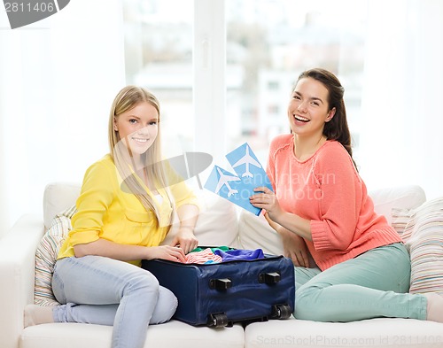 Image of two smiling teenage girls with plane tickets