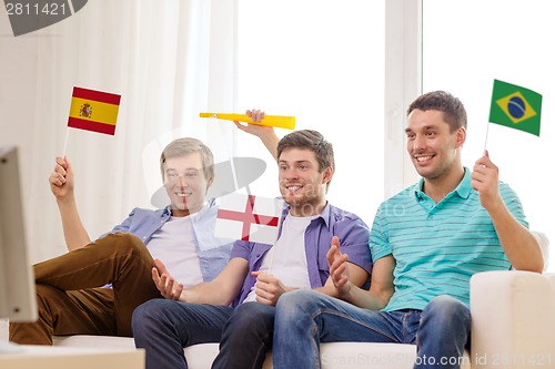 Image of happy male friends with flags and vuvuzela