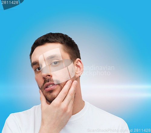 Image of beautiful calm man touching his face