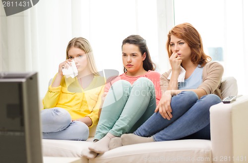 Image of three sad teenage girl watching tv at home