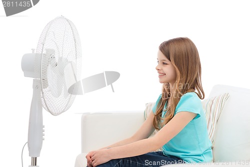 Image of smiling little girl with big fan at home