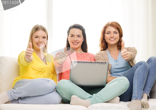 Image of three smiling teenage girls with laptop at home