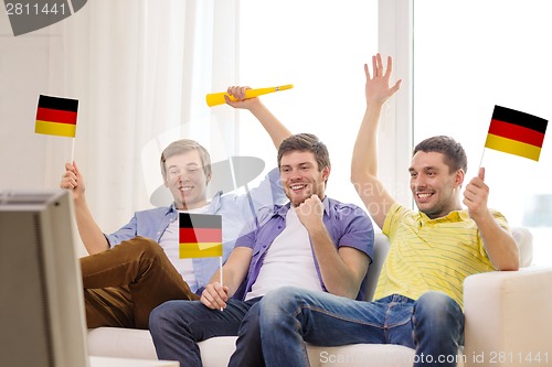 Image of happy male friends with flags and vuvuzela