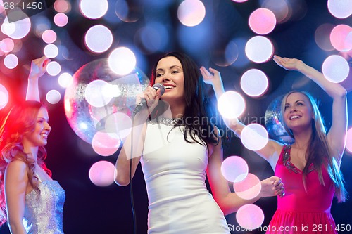 Image of three smiling women dancing and singing karaoke