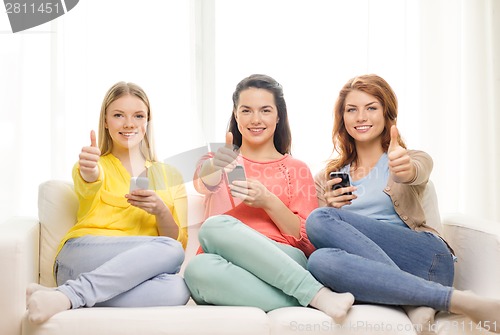 Image of smiling teenage girls with smartphones at home