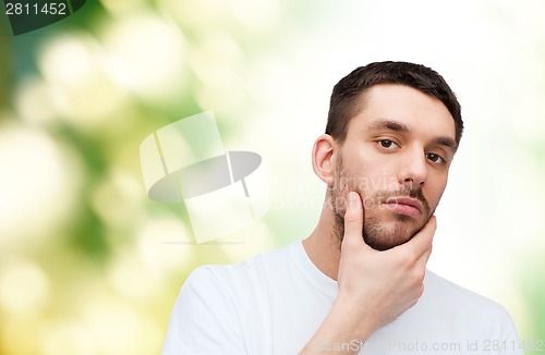 Image of beautiful calm man touching his face