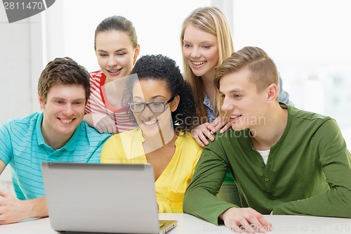 Image of smiling students looking at laptop at school